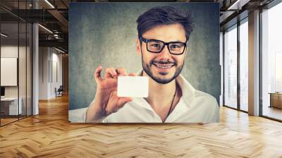 Smiling man showing blank card at camera Wall mural