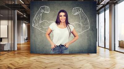 Strong happy young woman flexing her muscles Wall mural