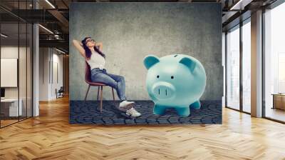 woman with big piggy bank relaxing sitting on chair Wall mural