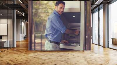 Young happy man using ATM Wall mural