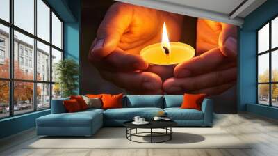 Close up of hands holding a lit candle in the dark Wall mural