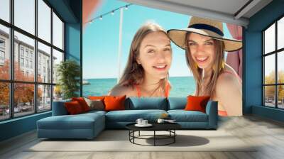 two smiling young women on beach making selfie Wall mural