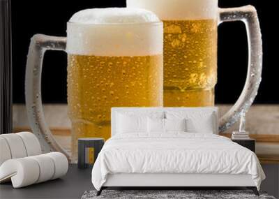 Two draft beer mugs on wooden table and black background Wall mural