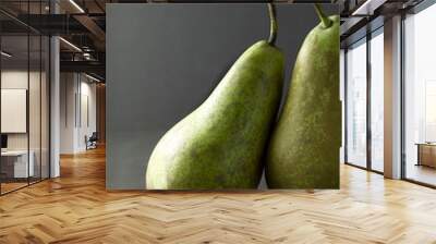 Two green pears on dark background with one resting on the other  Wall mural