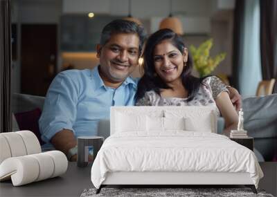 Happy middle aged couple using laptop computer relaxing on couch at home. Smiling mature man and woman talking having fun laughing with device sitting on sofa in sunny living room. Candid shot Wall mural