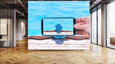 Making photos by smartphone of the girl in swimming pool Wall mural