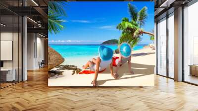 Two women with hats enjoying sun holidays on the tropical beach Wall mural