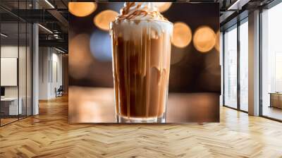 A glass of iced caramel macchiato with a layer of caramel cream floating on top and ice on the rim of the glass. Wall mural