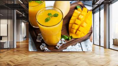 Refreshing and healthy mango smoothie in a glass with mango on white wooden background. Wall mural