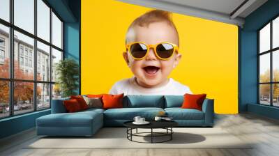 Funny baby boy wearing big sunglasess isolated on yellow background Wall mural