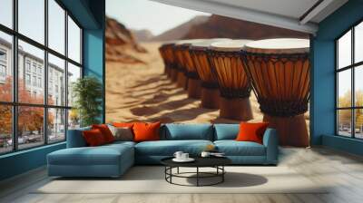 A row of African drums in the desert, surrounded by soft dunes and jagged rocks, deep shadows creating a dramatic contrast with the instruments, Cinematic, High contrast Wall mural