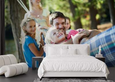 Happy family laying in hammock in woods Wall mural