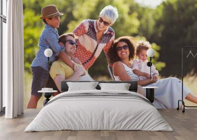 Multi-generation family relaxing in sunny field Wall mural