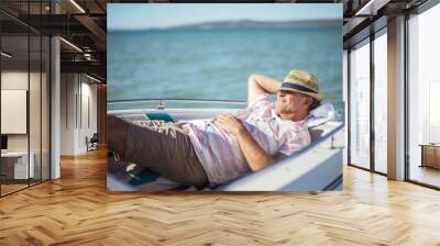 Older man relaxing in boat on water  Wall mural