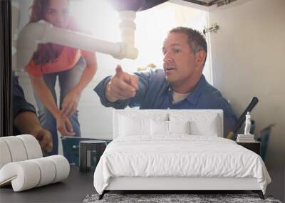 Plumbers working on pipes under sink Wall mural