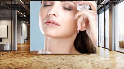 Beautiful woman applying ice cube treatment on face Wall mural