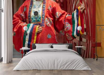 detail of traditional Vietnamese red silk robes. Model is standing next to a red gate. These robes were worn by royalty Wall mural