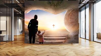 Easter and Good Friday concept, Mom and child standing with empty tomb of Jesus Christ at cross on sunset background Wall mural