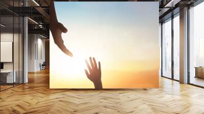 Hand reaching out to help someone on sunset sky background. Wall mural