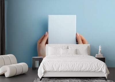 Minimalist scene with a woman holding a blank brochure, viewed from the top on a grey background, ideal for mockups, sharp detail and smooth lighting Wall mural