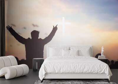 Praise and worship concept: Silhouette human raising hands to praying God on blurred cross with crown of throne sunset background Wall mural