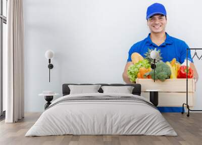 Closeup portrait of asian couple delivery man woman in blue uniform hold fresh grocery vegetables food isolated on white. Healthy lifestyle shopping internet online supermarket delivery teamwork Wall mural