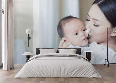 Closeup portrait of beautiful young asian mother kissing her newborn baby on hospital bed. Healthcare medical family love lifestyle breastfeeding nursery mother’s day together concept Wall mural