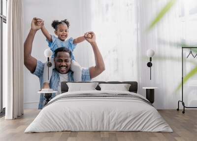 Happy black African American father daughter playing at home living room. Afro man carry piggyback little toddler girl. Cheerful family bonding together father’s day concept banner with copy space Wall mural