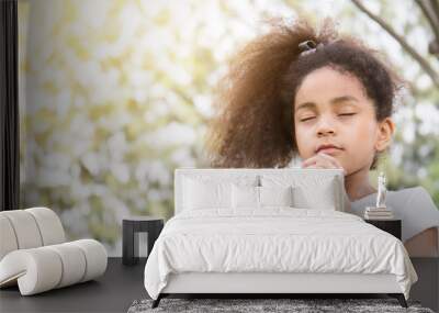 Portrait of little cute girl praying in the park, young girl with her hands together, closeup expression. Religion faith and believe concept banner Wall mural