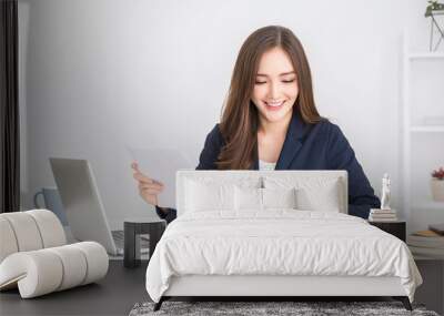 Portrait of young asian business woman paying bills online with laptop in office. Beautiful girl at desk with computer and chequebook. Startup businesswoman financial bank account concept Wall mural