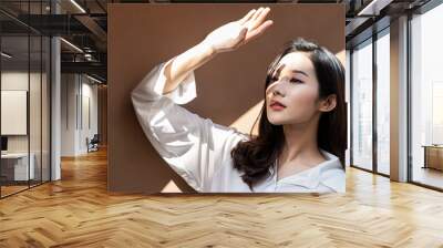 Portrait of young beautiful asian woman traveler hands protect face from sun light in fresh summer time. Happy cheerful asian girl in summer. Beauty sunscreen skin care make up model concept Wall mural