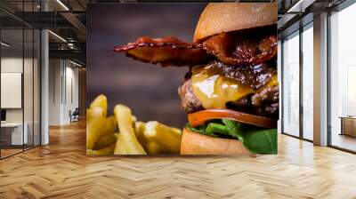 Craft beef burger with cheese, bacon, rocket leafs, caramelize onion and french fries on wood table and rustic background. Wall mural