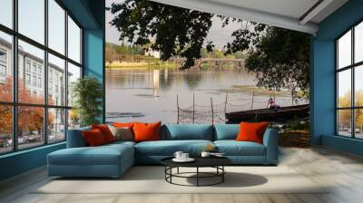 A summer day in the river with two fishemem on a boat and a mediavel stone bridge at background in North region of portugal Wall mural