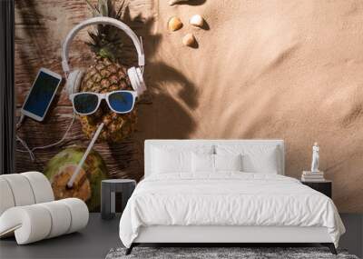 Ripe pineapple with sunglasses and headphones on beach sand Wall mural