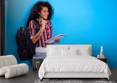 young african student with backpack on the back on blue background. Wall mural