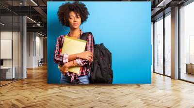 young african student with backpack on the back on blue background Wall mural