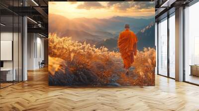 Buddhist monk in a colorful saffron robe walking on a mountain path, surrounded by tall grass, bathed in warm golden dramatic light Wall mural