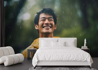 Image of positive young korean man smiling during rain in tropical forest. Cheerful male enjoying the rain outdoors. Wall mural