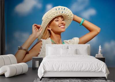 Fashion portrait of happy beautiful woman in hat over blue sky - close up Wall mural