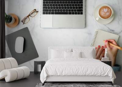 Flat lay workspace. Woman hand with coffee cup, smartphone, computer, notebook, planner and stationary with copy space on marble table background. Top view. Wall mural