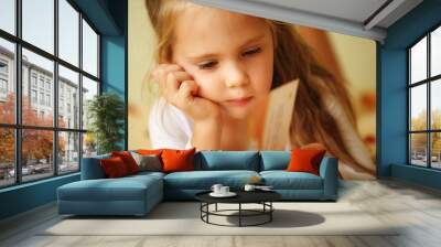 closeup of a little girl reading a book on her bed Wall mural