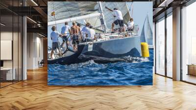 Dark sailing boat close to yellow buoy during the race Wall mural