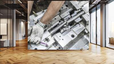 Detail of worker's hands tightenning the screw in repaired big steel mechanical device Wall mural