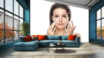 girl with clean skin apply cream on her face. Isolated on a white background Wall mural