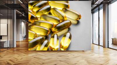 Omega 3 supplements in golden translucent natural softgel capsules for energy and well-being on a grey ceramic plate. Macro shot Wall mural