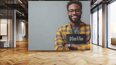 A cheerful man greets with a Hello sign in front of a gray wall Wall mural