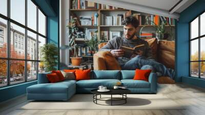 A man sitting on a couch, engrossed in reading a book Wall mural