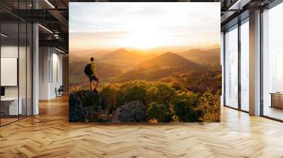 A hiker walking on a mountain meadow in spring or autumn. Hiking in the Lusatian mountains. Hiker, Backpacking on top of a mountain cliff landscape and trekking in it. Concept: Adventure, Art, Travel Wall mural