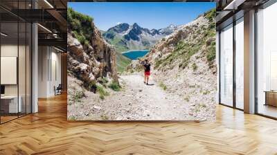 Hiker on the trail in the Alps mountains. Trek around blue lake surrounded by mountains in the Alps mountains and rocky trek. Lifetime experience on the hike  Wall mural