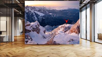 Successful hiker on top of mountain at sunrise or sunset. Gesture of triumph. Happy hiker in red. Climber on a summit freedom Wall mural